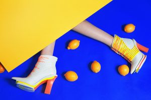 White boots with yellow heel shot creatively on blue and yellow backgrounds with lemons