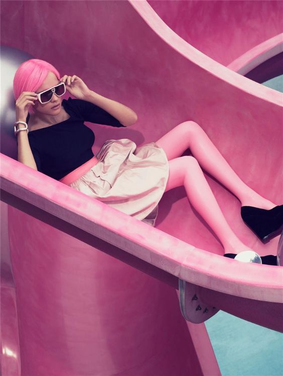 Model on a pink slide showing how eCommerce fashion photography can be benefit from unusual locations