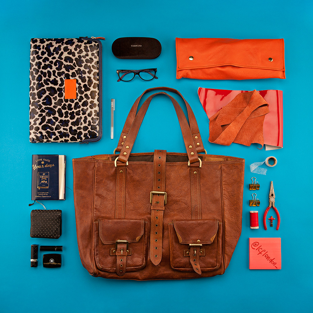 Photo of brown handbag with items that go inside give context to handbag product photography